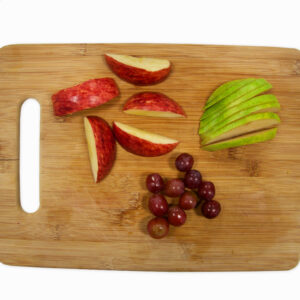 Apple slices and grapes on cutting board.