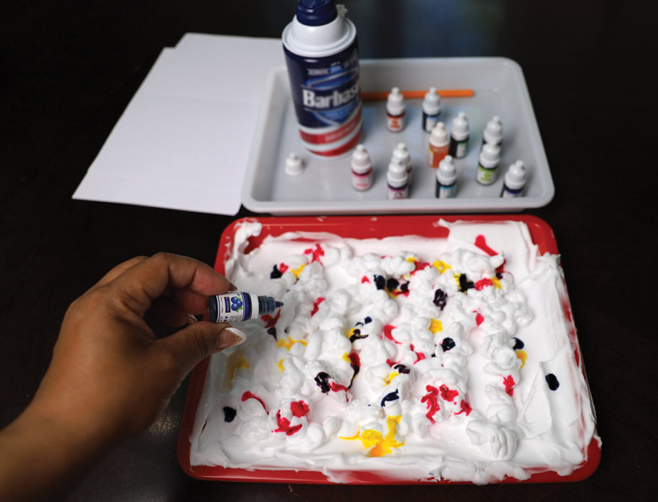 tray filled with shaving cream and covered in different drops of food dye