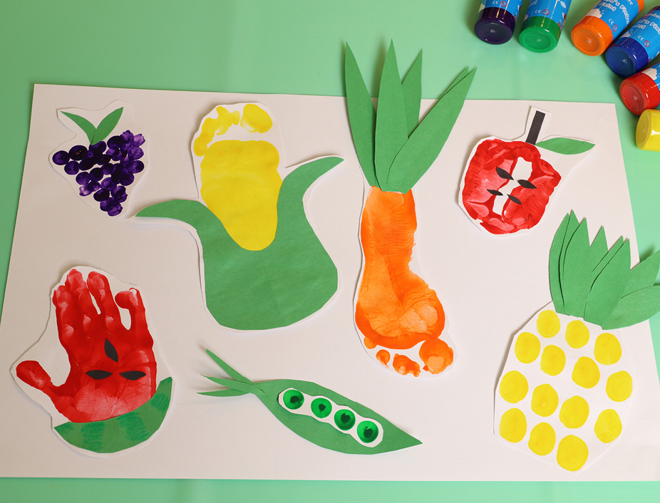 Final art work of fruits and veggies made out of child's painted handprint or footprint. Construction paper used for leaves or other parts of the fruit or veggies. All cut out and placed on a white piece of paper