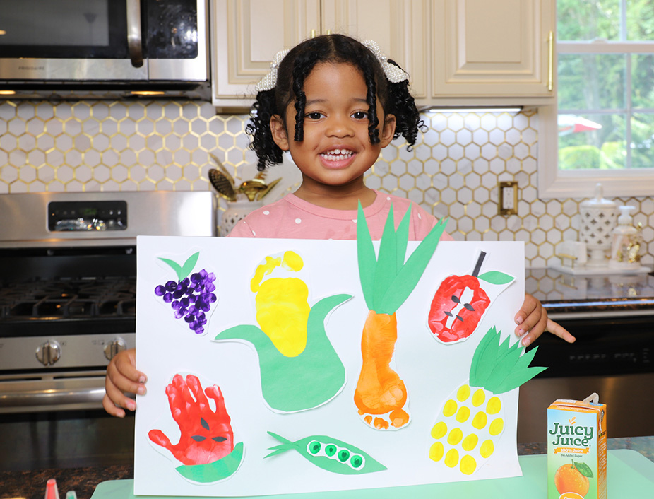 Little girl holding up her Fruit and Veggie Prints artwork garden