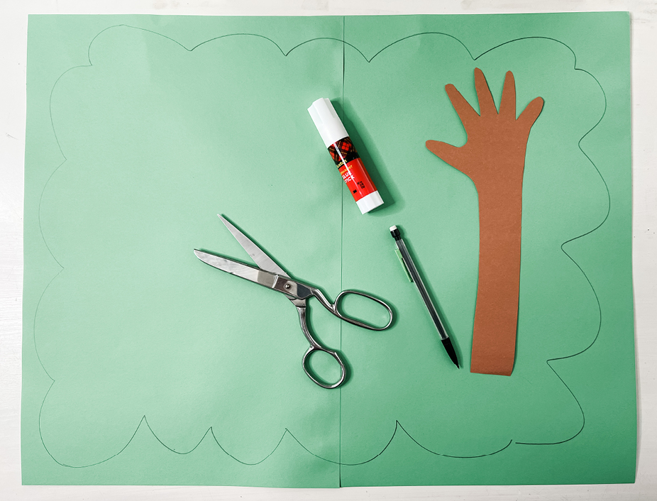 cutting green construction paper to make the trees bigger leaves to add to the trees trunk made out of your little ones hand-shaped tree trunk