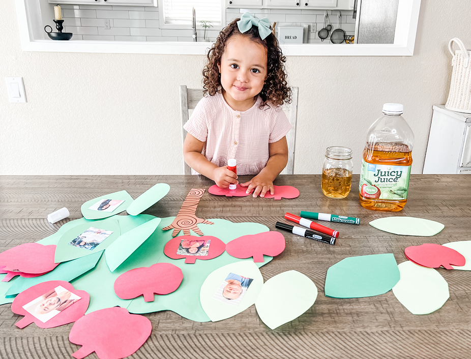 Small girl constructing her craft family tree with construction paper and family images