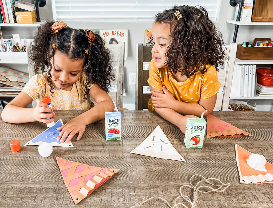 two young girls gluing their construction paper pies together