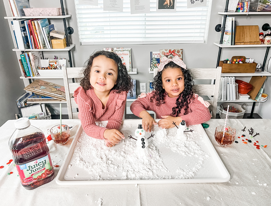 Young girls playing with the homemade snow and building a snowman drinking Juicy Juice 100% Juice