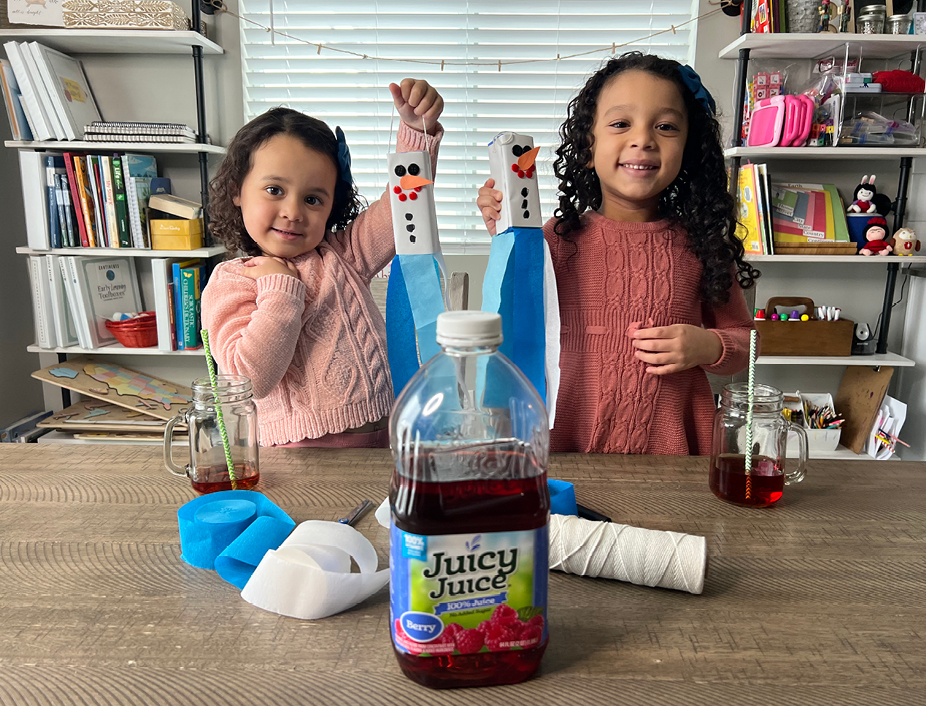 Two young kids holding up their finish snowman craft drinking Juicy Juice 100% Juice