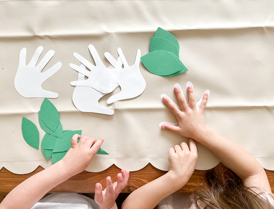 white hand and green leaves paper cut outs