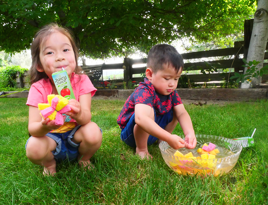 Young children palying with their resuable sponge water balloons and sipping juicy juice