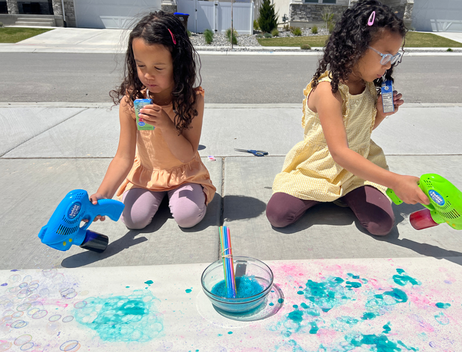 kids blowing bubble gun with onto paper to create bubble paint effects